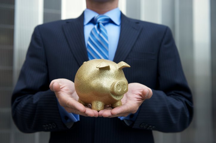 businessman holding a golden piggy bank outdoors